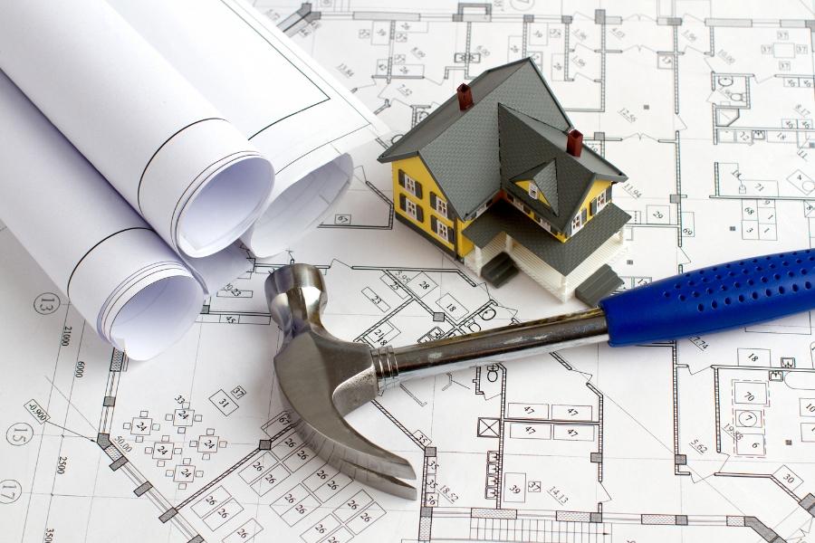 Building plans, a blue hammer, and a tiny house. 